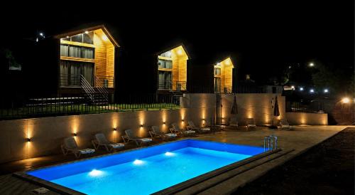 a swimming pool in front of a house at night at Sioni Hillside Cottages in Sioni