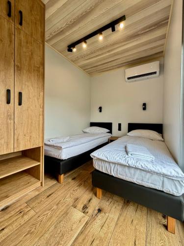 two beds in a room with wooden floors at Przystań Caryńska w Polańczyku in Polańczyk