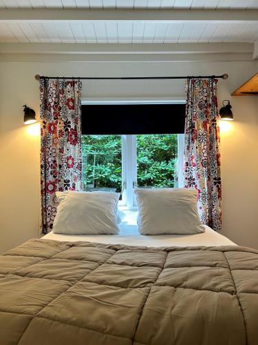 a bedroom with a large bed and a window at Kleine huisje op de Veluwe in Otterlo