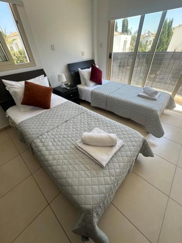two beds in a hotel room with towels on them at LC Palm Villa in Protaras