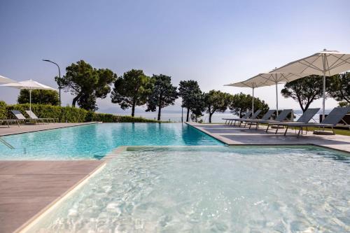 una grande piscina con sedie e ombrelloni di Vision Hotel a Peschiera del Garda