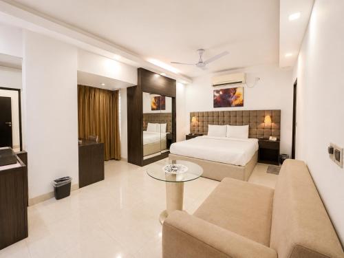 a bedroom with a bed and a couch and a table at Blossom Hotel Dhaka in Dhaka