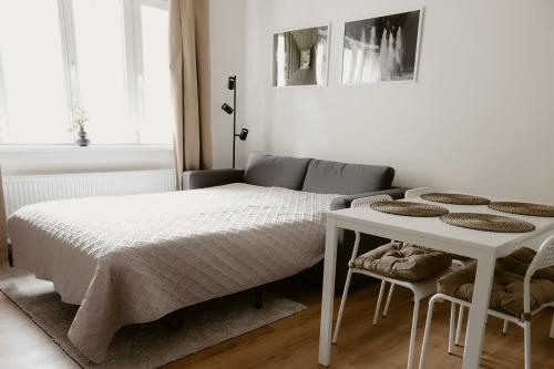 a white bedroom with a bed and a table at Apartmány park in Poděbrady