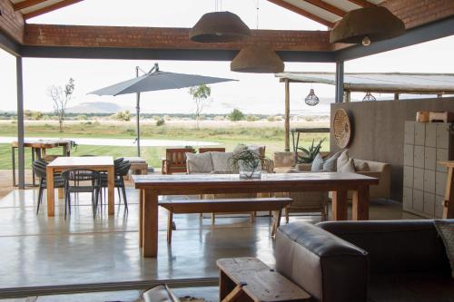 a living room with tables and chairs and a large window at Stroomrivier Lodge in Boshoek