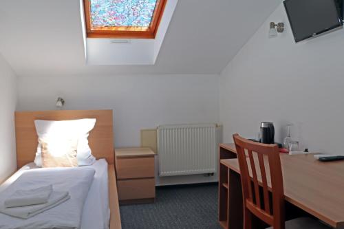 a bedroom with a bed and a desk and a window at Hotel Maria in Ostrava