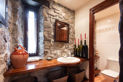 a bathroom with a sink and a stone wall at IZURRENEA Casa Rural in Arano