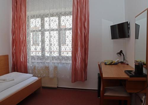 a room with a bed and a desk and a window at Hotel Maria in Ostrava