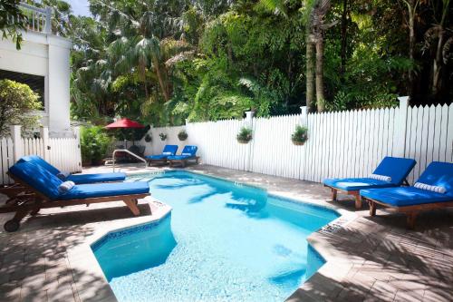 a swimming pool with blue chairs and a fence at Weatherstation Inn Circa 1911 in Key West