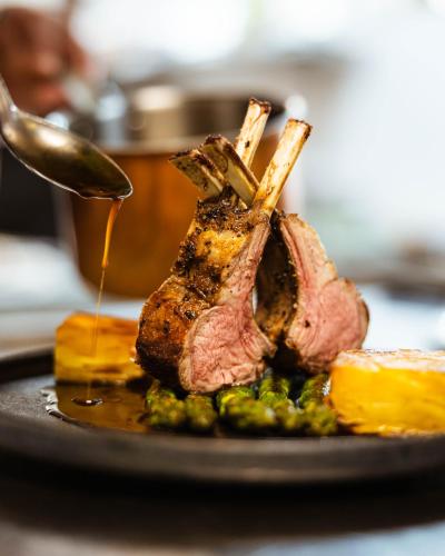 a piece of meat being drizzled with sauce on a plate at ARCOTEL Wimberger Wien in Vienna