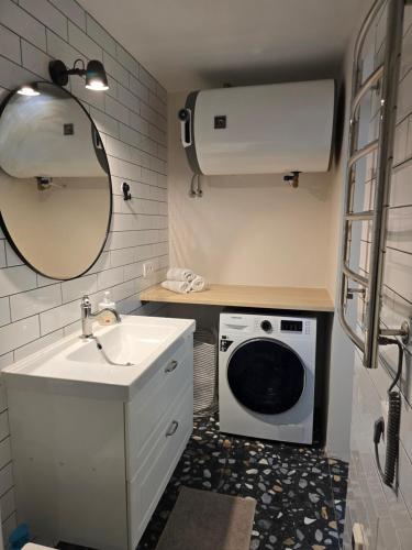 a bathroom with a sink and a washing machine at Vilimiškės Apartamentai in Palanga