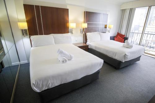 a hotel room with two beds with white sheets at Beachside Studio with Stunning Ocean View in Gold Coast