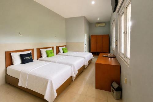 two beds in a room with two windows at Urbanview Hotel RDN Oasis Cisarua by RedDoorz in Brujul