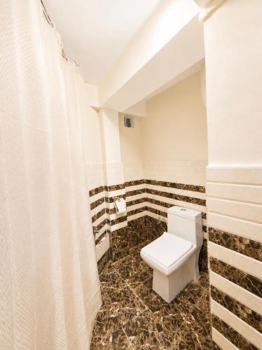 a bathroom with a toilet and a shower curtain at Ananda Homestay in Tawang