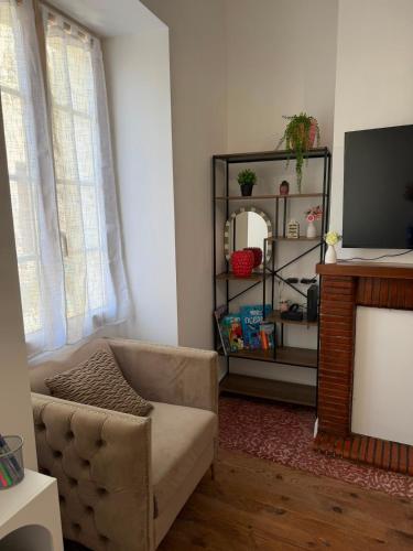 a living room with a couch and a television at Maison des Capucins in Nérac