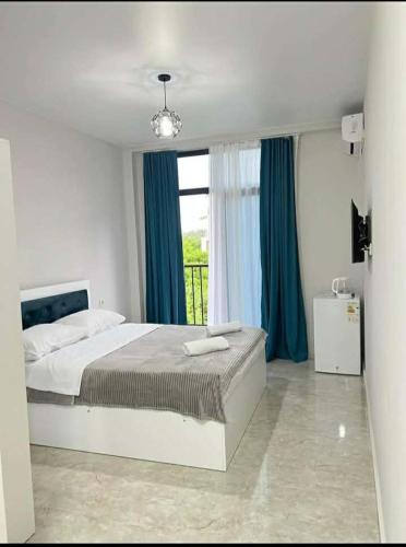 a bedroom with a bed with blue curtains and a window at Relax inn in Kobuleti