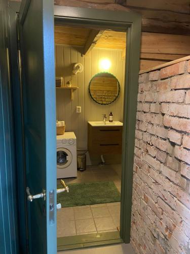 a door to a bathroom with a sink and a washing machine at Gårdshus på Kilagårds Gröna in Heberg