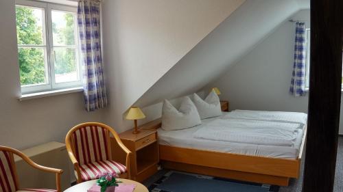 a bedroom with a bed and a chair and a window at BohnApartments Vogelmühle Ilsenburg in Ilsenburg