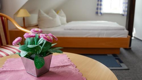 a vase with flowers on a table in a bedroom at BohnApartments Vogelmühle Ilsenburg in Ilsenburg