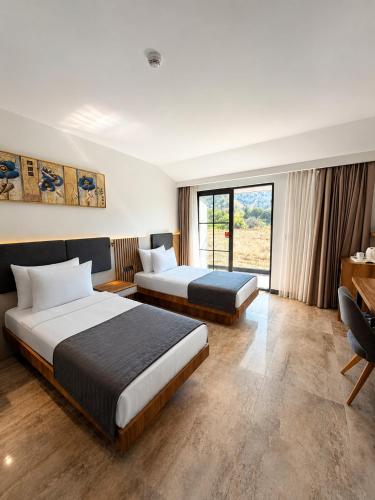 a hotel room with two beds and a desk at Pamukkale Kaya Termal Otel in Pamukkale