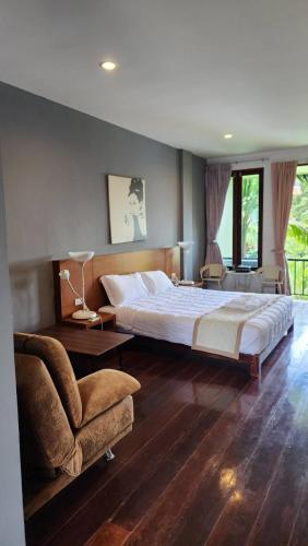 a large bedroom with a large bed and a chair at Utime Riverside Kanchanaburi in Ban Yang (2)