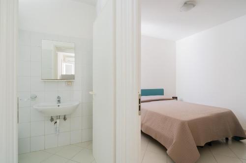 a white bathroom with a bed and a sink at La villetta 451 in Fontanelle