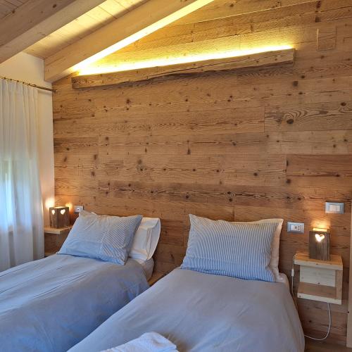 two beds in a room with a wooden wall at Cesa de Conesel in Colle Santa Lucia