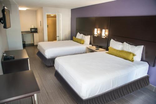 メルボルンにあるAtlantic Innのベッド2台とテレビが備わるホテルルームです。
