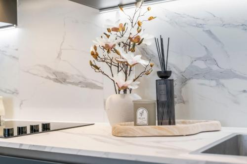 a white vase with flowers and a candle on a counter at Stylish 1-Bed flat with Private Balcony in Hatch End