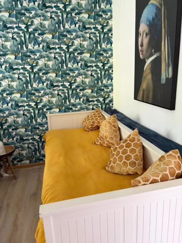 a bed with four pillows and a painting of a woman at Les studios du Domaine d'Eva in Libramont