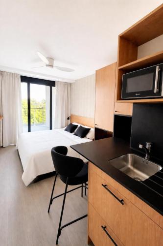 a hotel room with a bed and a kitchen with a sink at Sweetly La Rochelle in La Rochelle