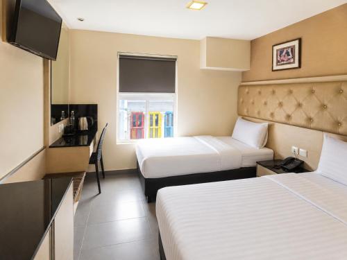 a hotel room with two beds and a television at Sandpiper Hotel Singapore in Singapore