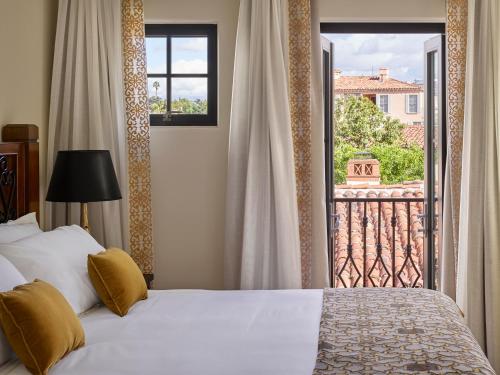 a bedroom with a bed and a balcony with a window at Plaza la Reina in Los Angeles