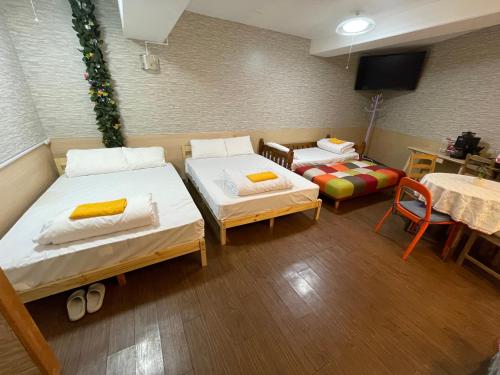 a room with two beds and a table and a couch at Shinjuku Sky hostel in Tokyo