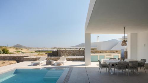 a villa with a swimming pool and a table and chairs at Alkinoe Villa Paros in Isterni