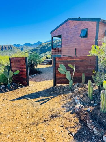 a house in the desert with a fence and cactus at Matilo Cabins - Cactus Deck with Hot-tub and Fireplace in Calitzdorp