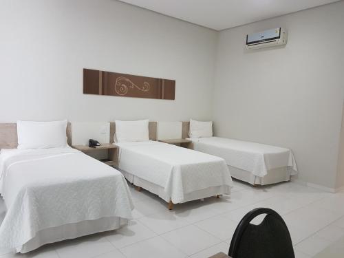 a room with two beds with white sheets at Portinari Palace Hotel in Vilhena