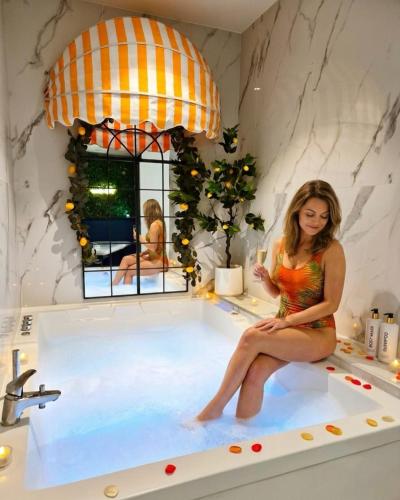a woman sitting in a bath tub with a glass of wine at Ciao Bella Wellness Suite - Luxury Jacuzzi, Massage Table & AC in Central Nice in Nice