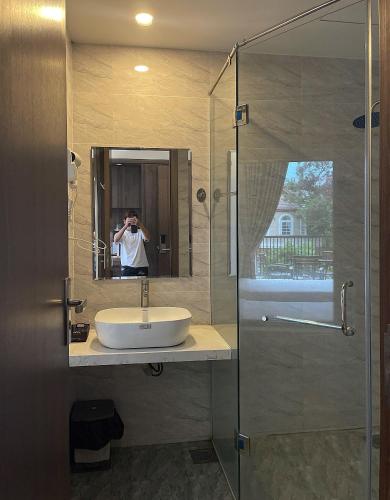 a man taking a picture of a sink in a bathroom at Mimosa Forest Hotel Villa in Xuan An