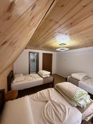 three beds in a room with wooden ceilings at Guesthouse Alpini in Lëpushë