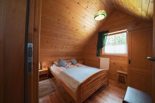 a bedroom with a bed in a wooden cabin at Domek na Górkach in Krościenko