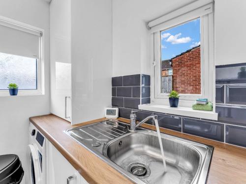 a kitchen with a sink and two windows at LetSavvy Contractor Accommodation Hartlepool in Hartlepool