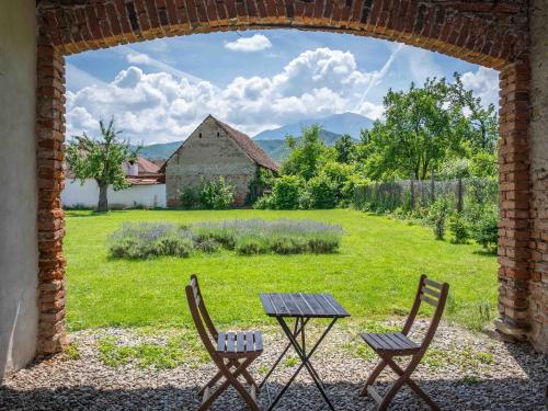 an archway with two chairs and a table and a field at Curte la Munte - charming village house in Sebeşu de Sus