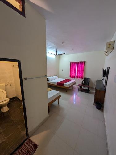 a room with a bed and a room with a toilet at Sona Rooms in Tiruchirappalli