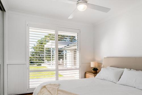 a white bedroom with a bed and a window at The Bower - Byron Hinterland in Teven
