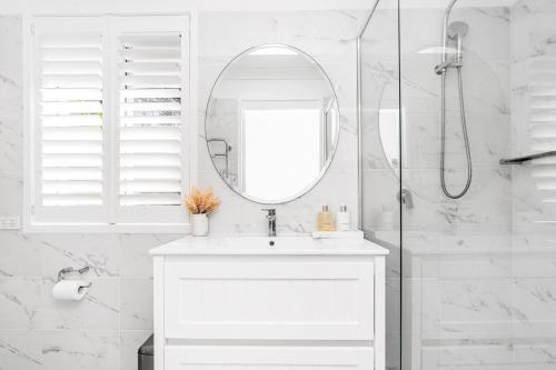 a white bathroom with a sink and a mirror at The Bower - Byron Hinterland in Teven