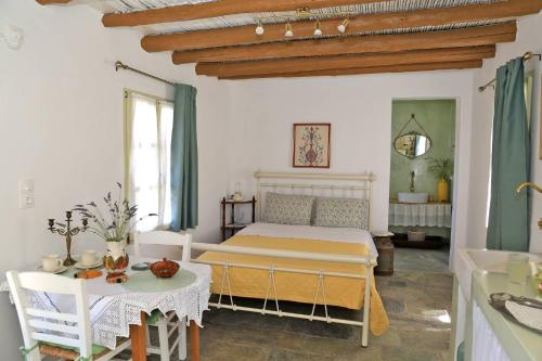a bedroom with a bed and a table and chairs at Oak Farm Guest House Junior in Andros