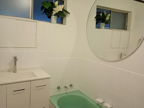 a bathroom with a tub and a sink and a mirror at Budget Friendly Accommodation in Mandurah