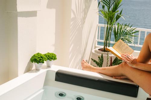 a woman sitting on a window sill reading a book at Hotel Helios Costa Tropical in Almuñécar