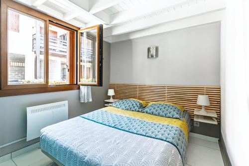 a bedroom with a bed and two windows at Villa Lolo, Piscine et Terrasse in Moliets-et-Maa