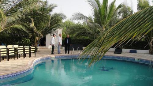 two men are standing next to a swimming pool at Eco-Lodge Hotel Oasis Fishing in Saint-Louis